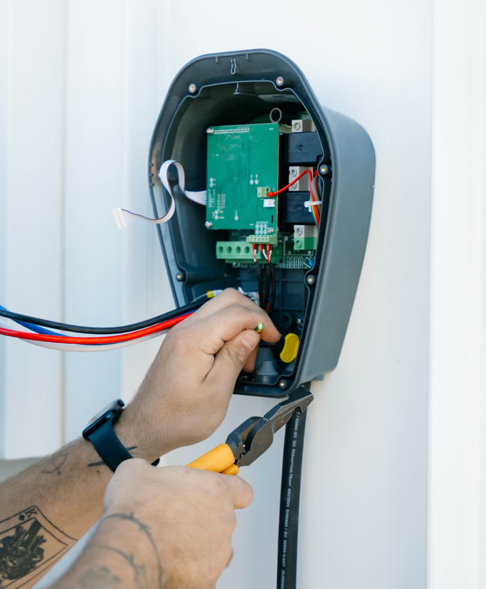 Wiring a black EV charger, cover off, with pliers